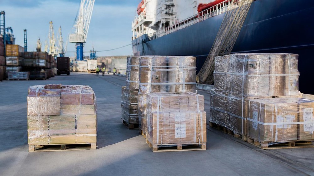 Shrink-wrapped pallets of bonded stores on the quay beside a vessel